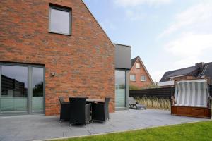 a patio with a table and chairs next to a brick building at MeerVerliebt C in Hörnum