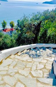 un patio de piedra con vistas al agua en Villa Athena Skiathos, en Megali Ammos