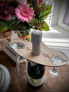 Li Ter Hôtel في مارش-أون-فامين: زجاجة من النبيذ و إناء من الزهور على طاولة