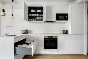 a white kitchen with white cabinets and a sink at Blueground Sarrià doorman newly renovated BCN-119 in Barcelona