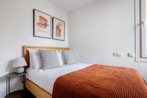 a white bedroom with a bed with a orange blanket at Blueground Sarrià doorman newly renovated BCN-119 in Barcelona