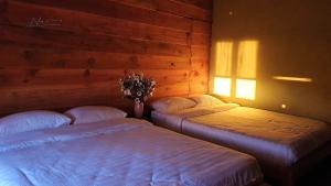 2 camas individuales en una habitación con pared en Tuyên Chiến Home - Nhà Gỗ en Ấp An Kroët