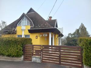 a yellow house with a wooden fence in front of it at Júlia Vendégház in Sárospatak