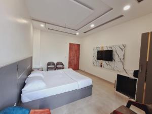 Schlafzimmer mit einem Bett und einem Flachbild-TV in der Unterkunft C T Heights Inn in Bharatpur