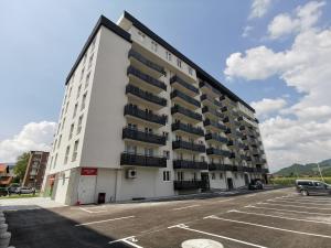 a white building with balconies in a parking lot at Apartman 33 in Kiseljak