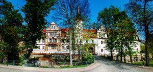 een groot wit gebouw met bomen ervoor bij Hotel Schloss Schkopau in Schkopau