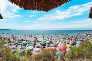 una multitud de personas en una playa con sombrillas en Riviera Fort Beach Apartments en Ravda