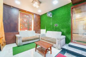 una sala de estar con 2 sillas y una pared verde en FabExpress Raj Supreme Residency en Chennai