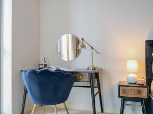 een blauwe stoel naast een bureau met een spiegel bij Stylish Urban Sanctuary with Parking in Londen