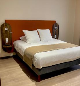 Schlafzimmer mit einem großen Bett mit einem Kopfteil aus Holz in der Unterkunft Hôtel du Commerce-restaurant au Couteau in Nogent