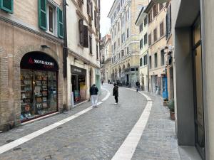 two people walking down a cobblestone street with buildings at Ankon Apartment Palazzo Mazzini in Ancona