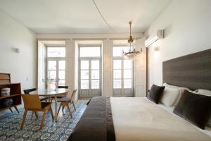 ein Schlafzimmer mit einem großen Bett, einem Tisch und Stühlen in der Unterkunft Palácio Fenizia Lux Apartments in Porto