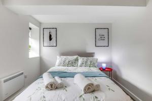 Luton Cozy & Lovely Stay for Contractors في لوتون: غرفة نوم بيضاء مع سرير عليه مناشف