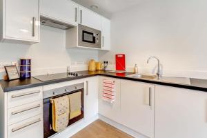 una cocina con armarios blancos y fregadero en Luton Cozy & Lovely Stay for Contractors en Luton