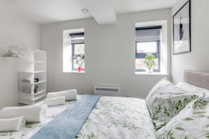 Luton Cozy & Lovely Stay for Contractors في لوتون: غرفة نوم بيضاء بسرير كبير ونوافذ