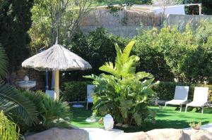 a garden with two chairs and an umbrella at The Red Farm Relais & Spa in LʼInglin
