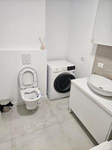 y baño con aseo y lavadora. en Cozy Apartments Avanera Suceava, en Suceava