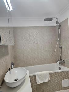 スチャヴァにあるCozy Apartments Avanera Suceavaのバスルーム(白いシンク、バスタブ付)