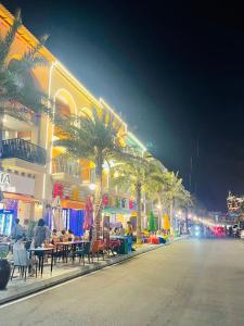 a street with tables and palm trees and a building at Novaworld Phan Thiết-7Days mart in Phan Thiet