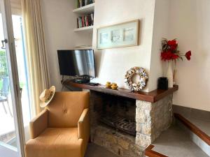 a living room with a fireplace with a television and a chair at Breda 4a in Torroella de Montgrí