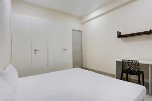 OYO Gaur Nitay في Dahmi: غرفة نوم بيضاء بسرير وكرسي
