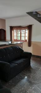a black couch in a living room with a window at Chácara Recanto das Pedras in Guarulhos
