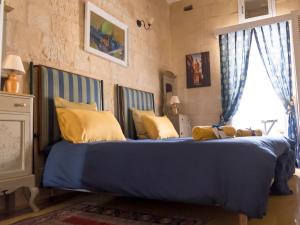 Un dormitorio con una gran cama azul con almohadas amarillas en The Knight - Historical terraced house overlooking the central square, en Birgu