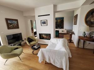 uma sala de estar com um sofá e cadeiras e uma televisão em Ciboure, villa avec piscine 8 couchages quatre étoiles em Ciboure