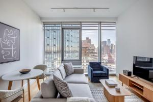 a living room with a couch and chairs and a tv at Blueground Midtown W gym nr hells kitchen NYC-1426 in New York