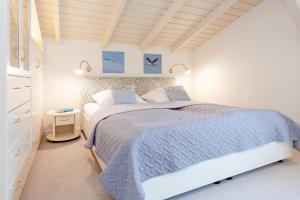 biała sypialnia z dużym łóżkiem i niebieskim kocem w obiekcie Annika w mieście Dahme