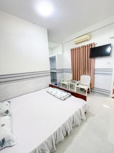 a bedroom with a large white bed and a chair at Kim Long Hotel in Phan Thiet