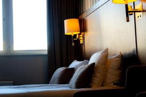 a bedroom with a bed with pillows and a window at Vänerport Stadshotell i Mariestad in Mariestad