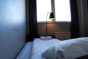 a bedroom with a bed with a lamp and a window at Vänerport Stadshotell i Mariestad in Mariestad