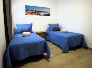 2 camas en una habitación con sábanas azules en Vv Salitre en La Santa