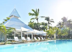 einen Pool in einem Resort mit weißen Stühlen und Sonnenschirmen in der Unterkunft Veranda Grand Baie Hotel & Spa in Grand Baie