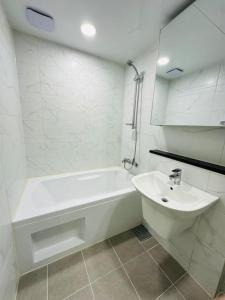 een witte badkamer met een bad en een wastafel bij JY House 1 in Busan