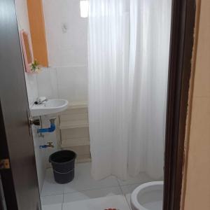 a bathroom with a white shower curtain and a sink at Titaays Surfers Inn in Baras
