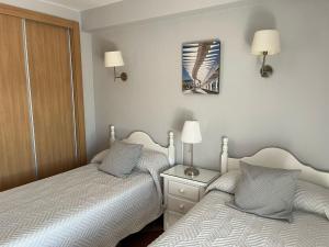 1 dormitorio con 2 camas y espejo en la pared en La Biznaga de María en Torre del Mar