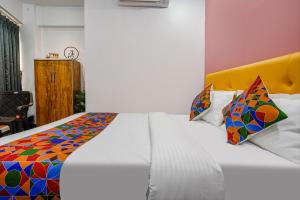 een slaapkamer met een wit bed en een kleurrijke quilt bij FabHotel Sky City in Surat