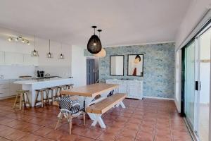 cocina con mesa de madera y sillas en una habitación en House Khasia- on the Golden Mile en St Helena Bay