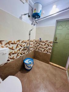 baño con aseo y puerta verde en Sunny Villa Cottage en Sivasagar
