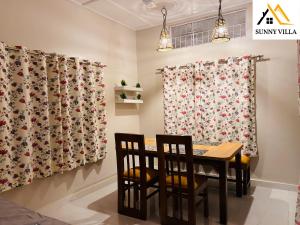 comedor con cortinas, mesa y sillas en Sunny Villa Cottage en Sivasagar