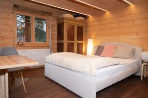 a bedroom with a white bed and a wooden wall at Kleines romantisches Chalet in der Semmering-Rax Region in Neunkirchen