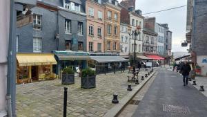 a city street with buildings and a person walking down the street at Studio cosy au cœur d'Honfleur in Honfleur