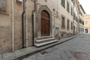 um edifício antigo com uma porta de madeira numa rua em Piazza dei Cavalieri Confortable Apartment em Pisa