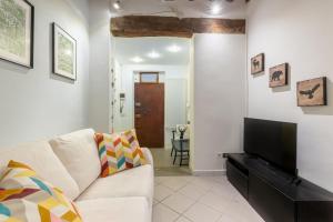 a living room with a white couch and a flat screen tv at Piazza dei Cavalieri Confortable Apartment in Pisa