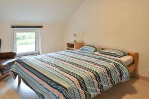 1 dormitorio con 1 cama con edredón a rayas y ventana en Gîte charmant en Ardennes !, en Neufchâteau