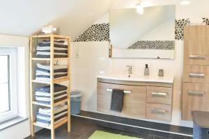 a bathroom with a sink and a shelf with towels at Gîte charmant en Ardennes ! in Neufchâteau