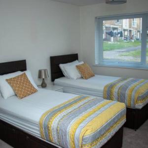 um quarto com 2 camas e uma janela em Crawley Apartment near Gatwick Manor Royal Newly Refurbished Sleeps 4 em Crawley
