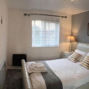 a bedroom with a white bed with a window at 2-Bed Sleeps 4 Comfy For Contractors With Free Parking in Crawley near Gatwick Manor Royal Refurbished in Crawley +22 photos